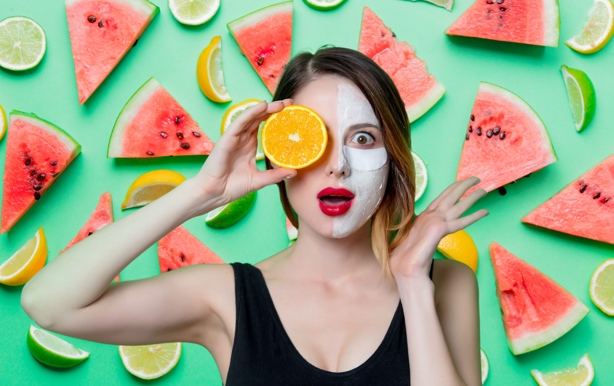 woman with skincare product on face and watermelon slices
